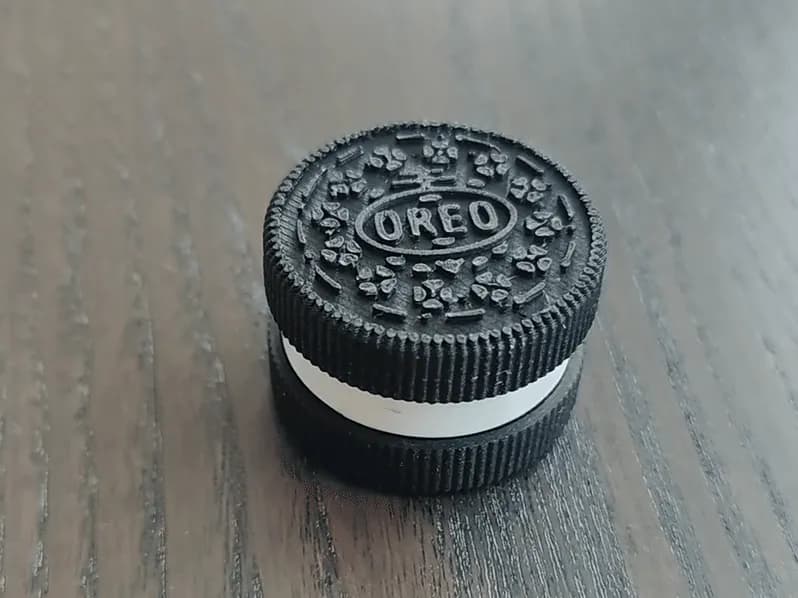 3D printed black Oreo cookie fidget clicker on a wooden desk