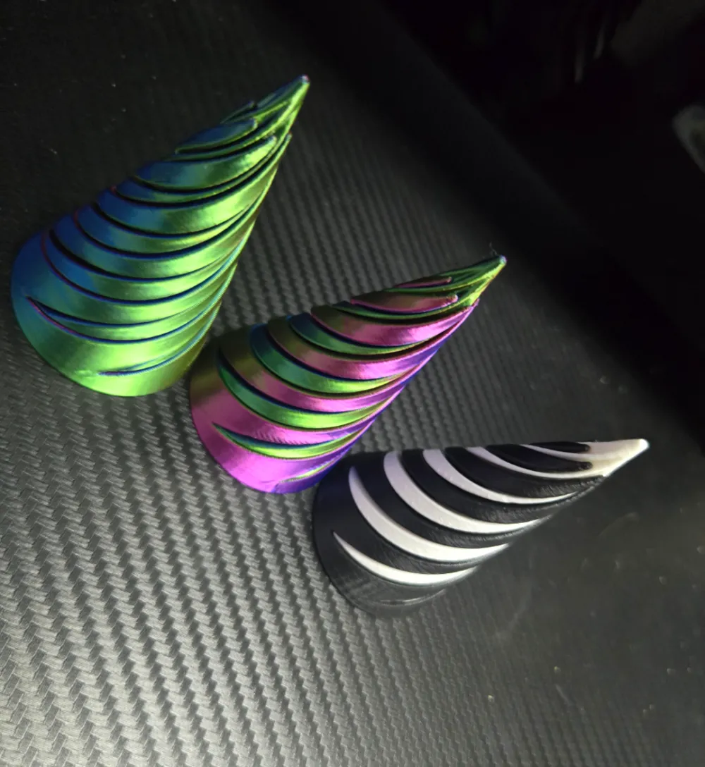 3D printed spiral fidget cones in rainbow silk, pink, and black and white PLA